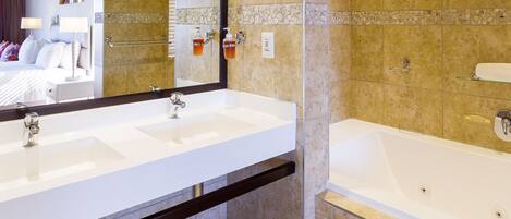 A modern bathroom with two sinks, a bathtub, and a large mirror.