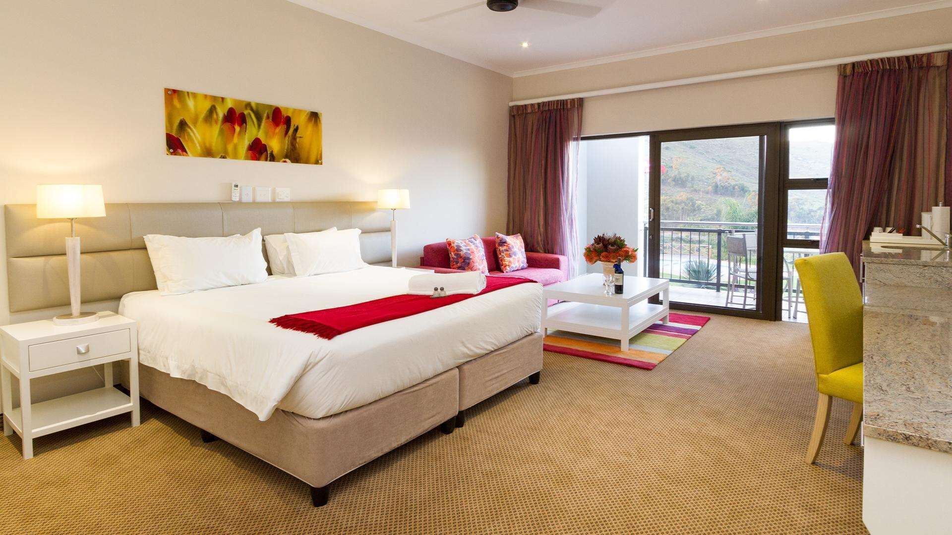 Una habitación de hotel moderna con una cama grande, un escritorio, una silla y un balcón con vistas.