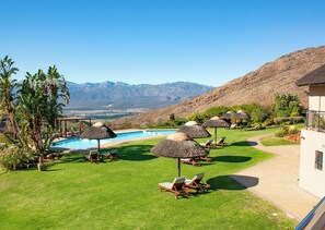 A poolside area with lounge chairs and umbrellas, a swimming pool, and a mountainous backdrop. - Piekenierskloof Mountain Resort by Dream Resorts (Bergrivier)