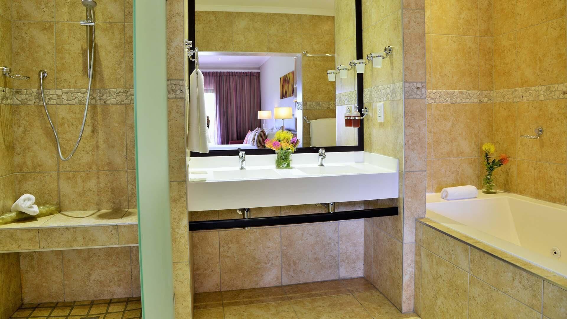A bathroom with a large mirror, a sink, a shower, and a bathtub.