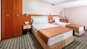 A hotel room with two beds, a wardrobe, a bedside table with a phone, and a nightstand with a lamp. - Mint Residence Taksim (Istanbul)