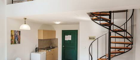 A modern interior with a kitchen, dining area, and a spiral staircase.