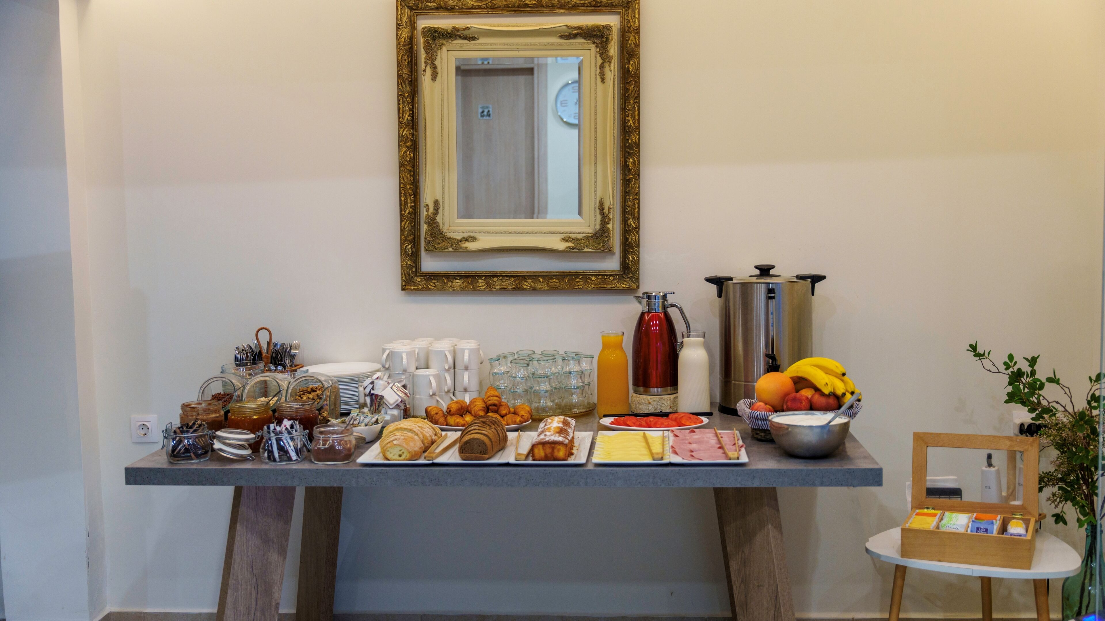 Un bufé de desayuno con diversas opciones de comida, una cafetera y un bol de fruta.