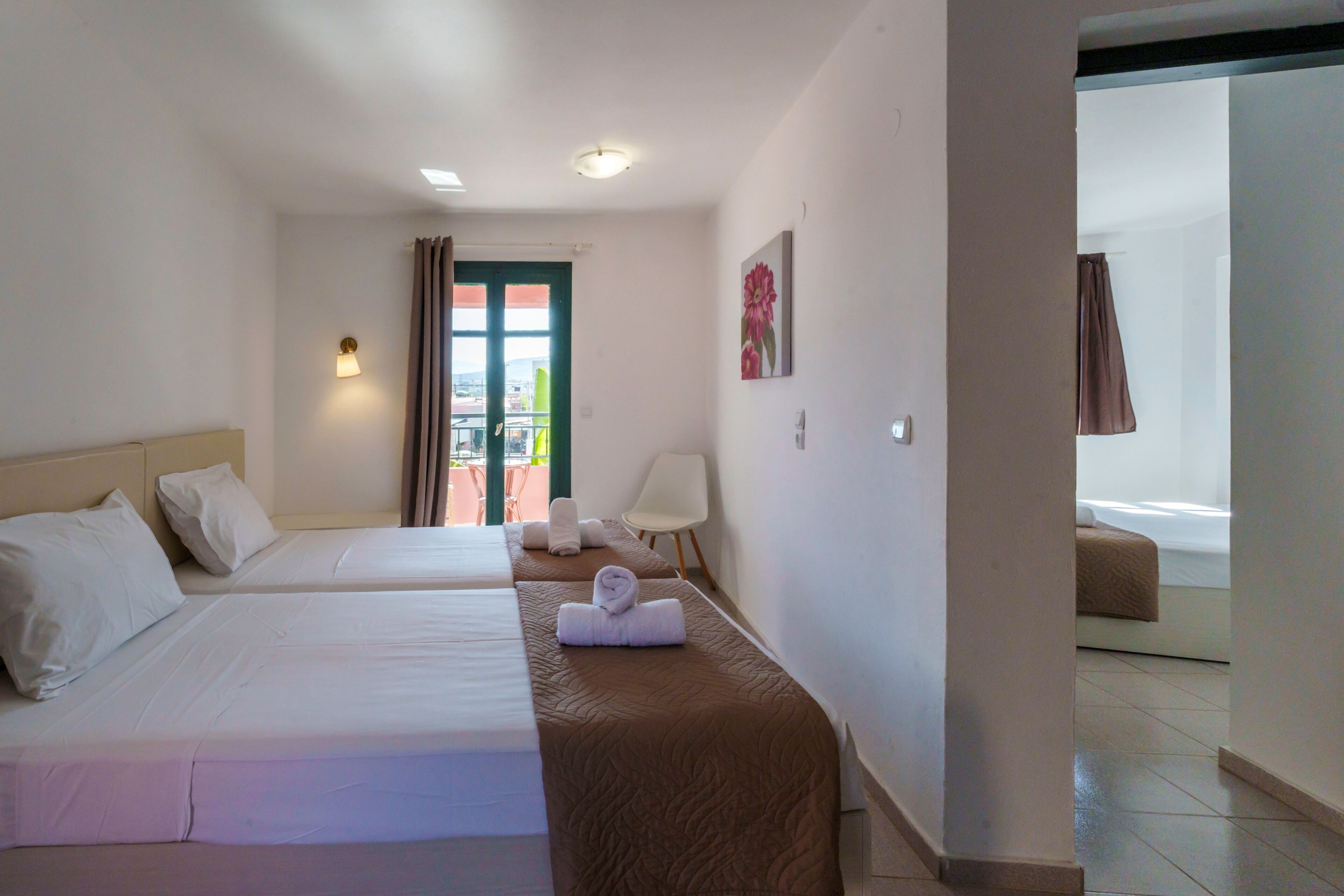 Une chambre d’hôtel avec deux lits, un coin salon, un balcon et une vue sur l’extérieur.