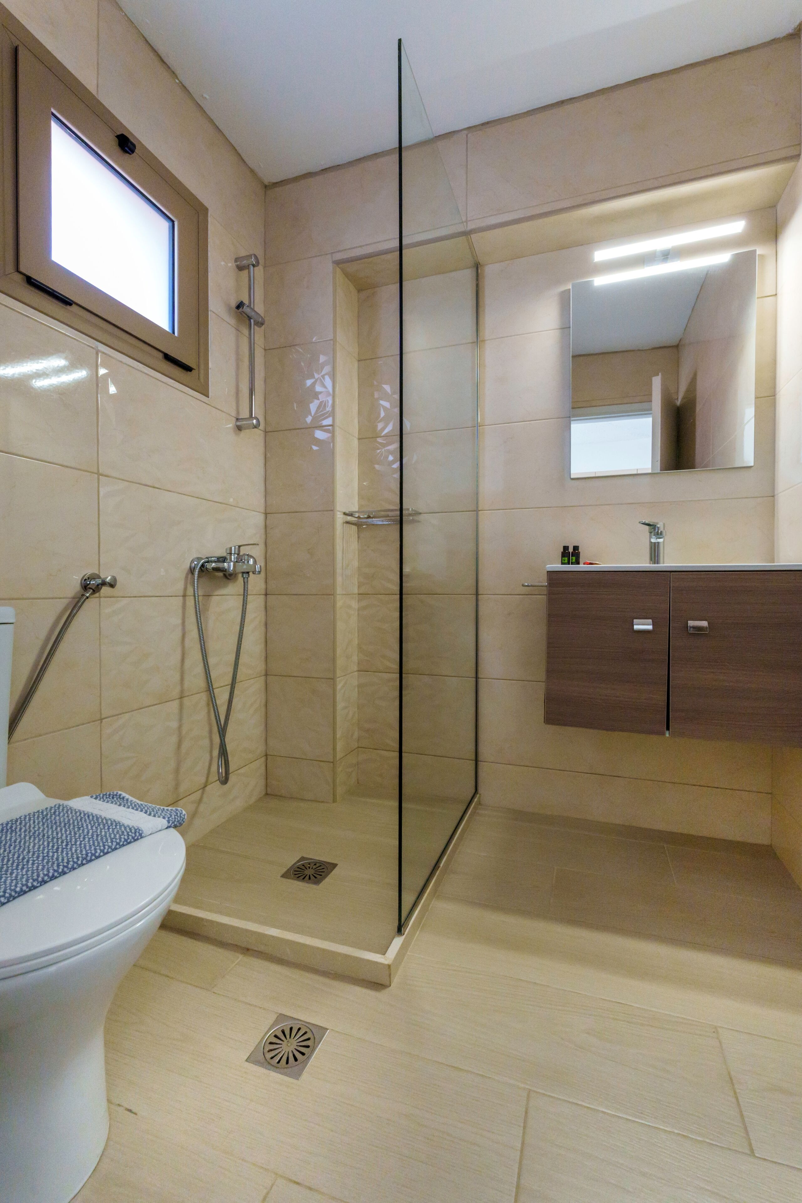 Un baño moderno con ducha envuelta en vidrio, inodoro y tocador con espejo.