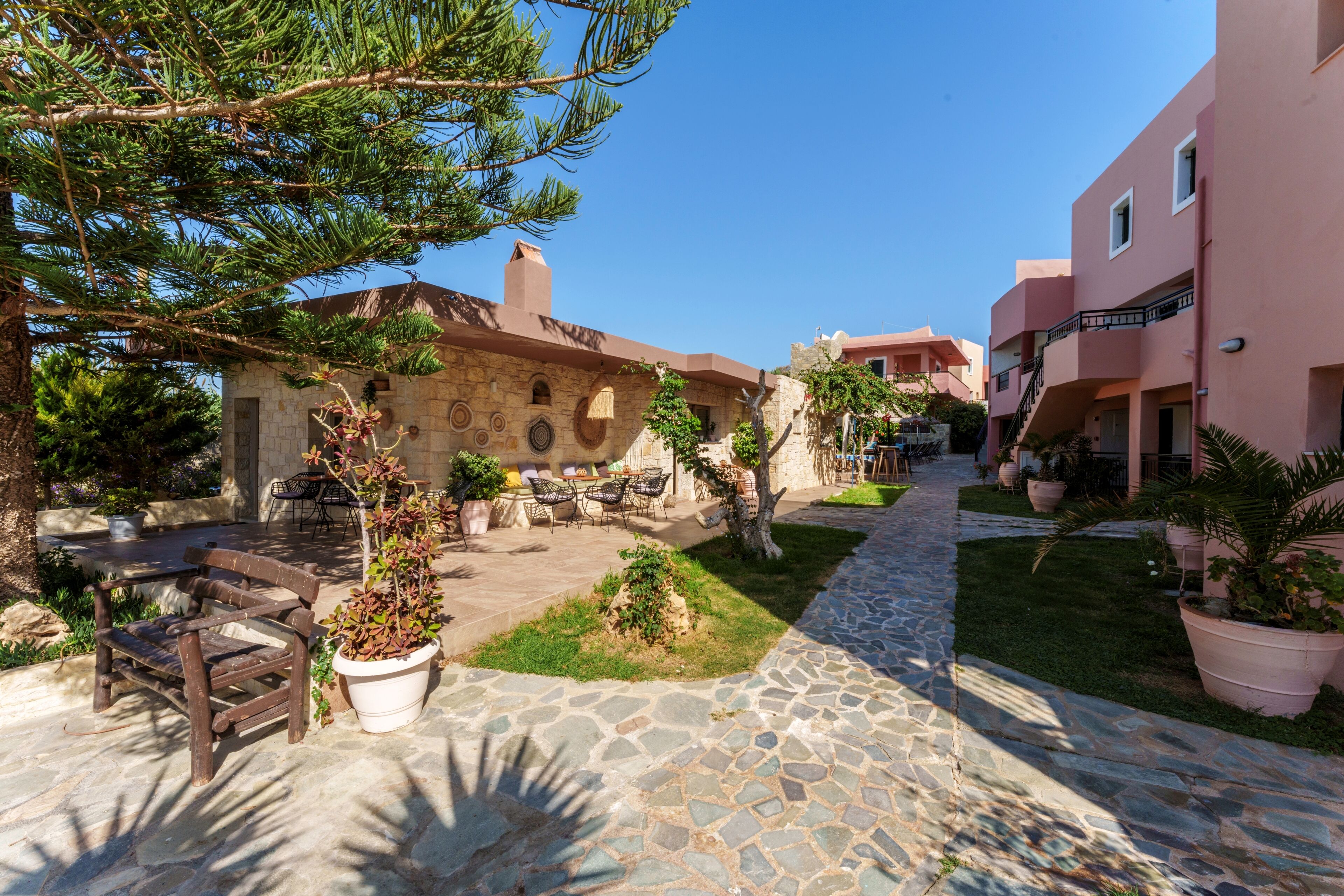 A courtyard with stone flooring, outdoor furniture, and potted plants.