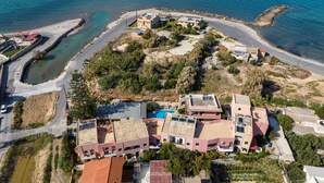 Vista aérea de una zona residencial costera con casas, una piscina y una carretera que conduce al mar.