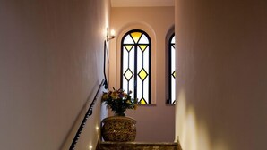 Eine Treppe mit Steinstufen, ein Blumentopf und ein Buntglasfenster im Obergeschoss.
