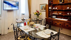 Ein Esszimmer mit einer Kronleuchter, einem Fernseher, einem Buffetschränkchen und einem Holzkasten.