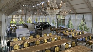 A grand hall with tables and chairs, chandeliers, and a vintage car. - Hotel Hirvihaaran Kartano (Maentsaelae)
