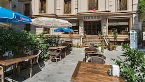 A hotel with outdoor seating, a Pepsi-branded umbrella, and a staircase leading to the entrance. - Grand Pamir Hotel (Istanbul)