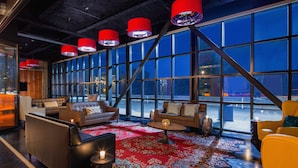 A modern lounge with leather sofas, a patterned rug, and red pendant lights. - Hotel Nyack, a JdV by Hyatt Hotel (Nyack)