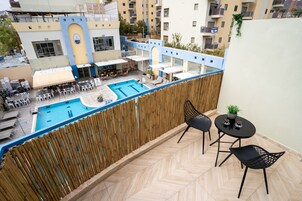 A balcony with a view of a swimming pool and outdoor seating area.