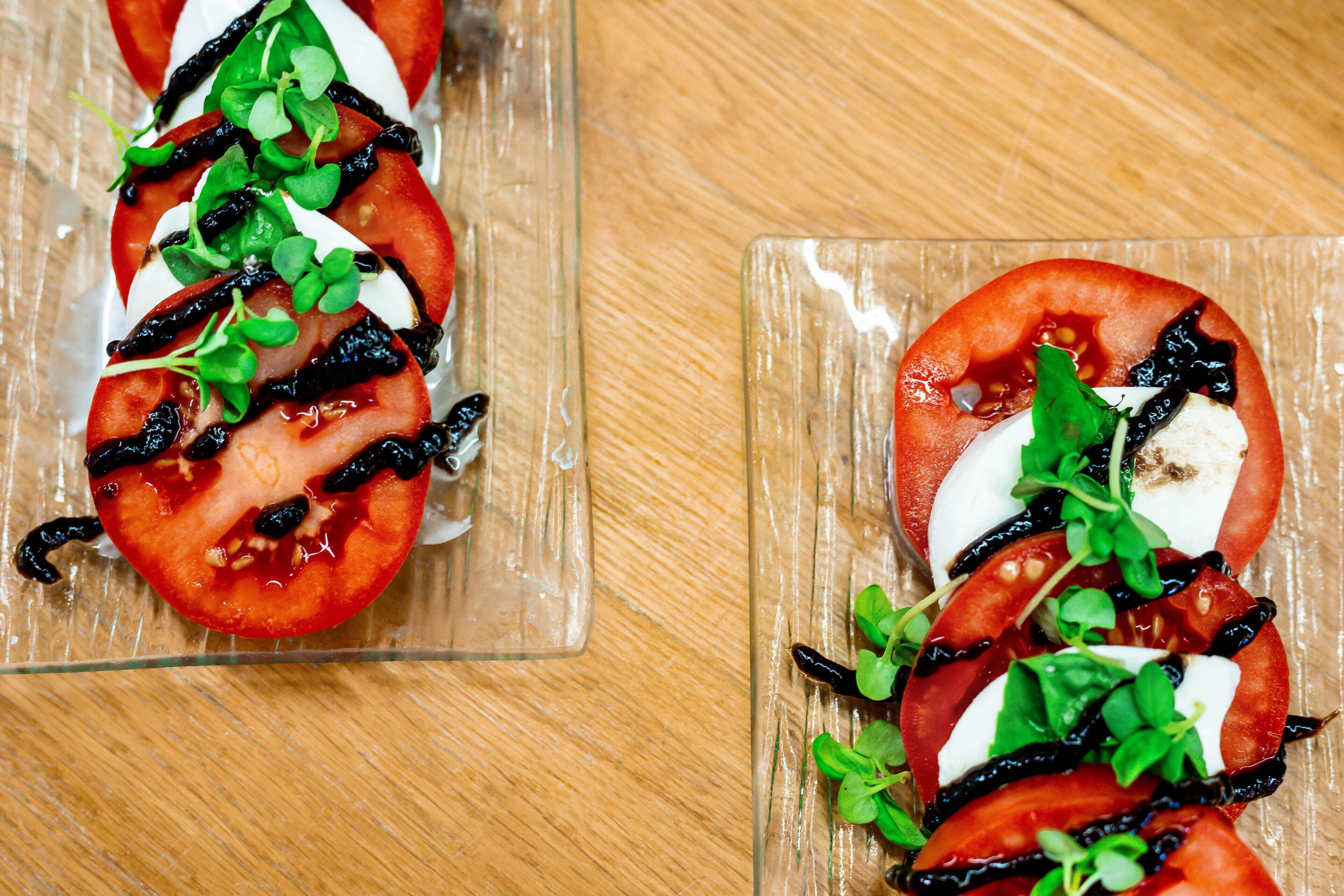 Dos platos de vidrio con ensalada de tomate y mozzarella.