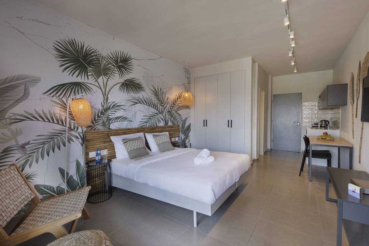 A modern bedroom with a large bed, a small table, a chair, and a desk.
