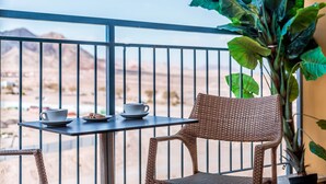 A balcony with a table and two chairs, a potted plant, and a view of a mountainous landscape. - Almog Eilat (Eilat)