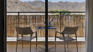 A balcony with wicker chairs and a table, a bamboo fence, and a view of mountains. - Almog Eilat (Eilat)