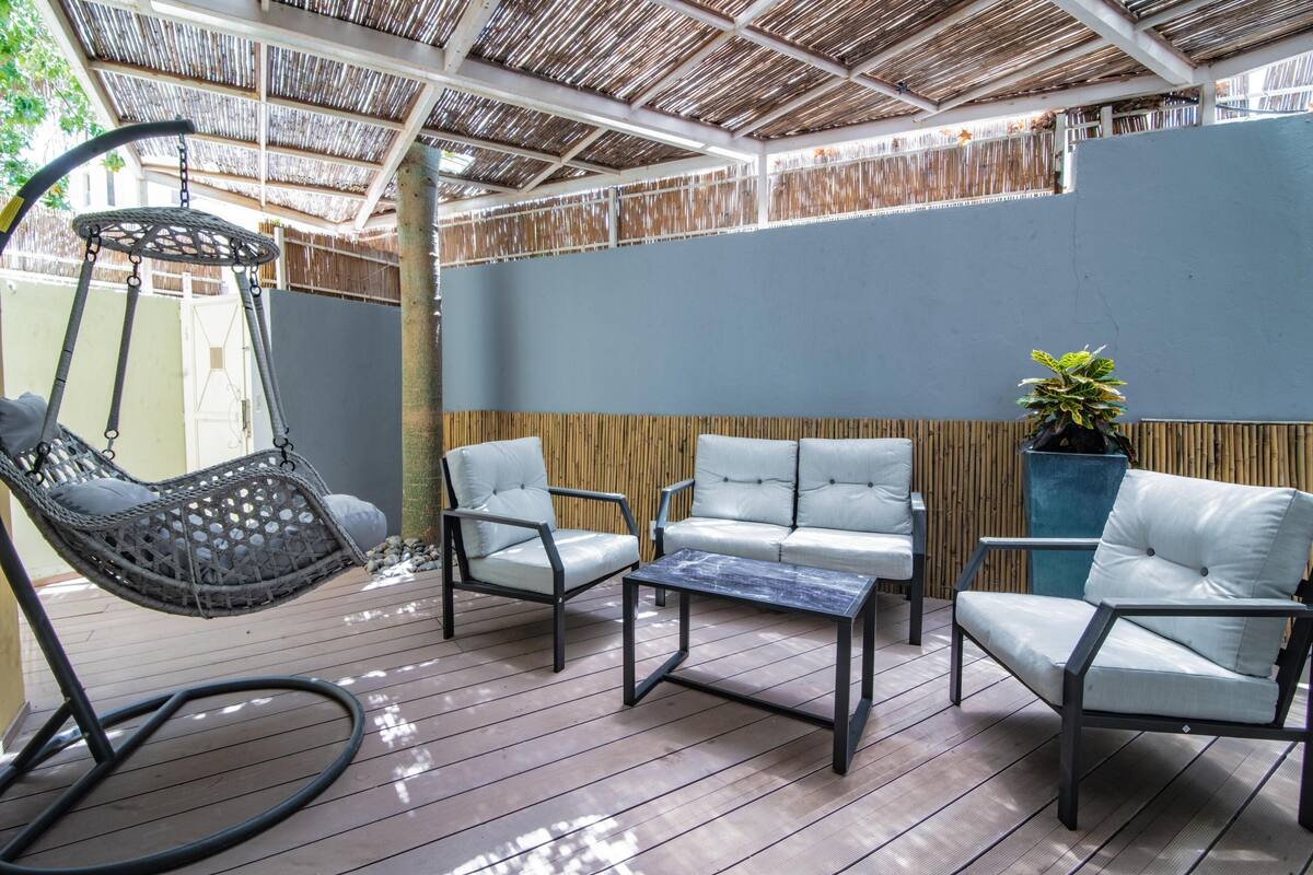 An outdoor patio with a hanging chair, two sofas, and a coffee table.