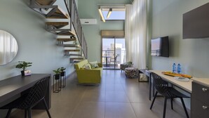 A modern living space with a staircase, a sofa, a dining table, and a TV. - Almog Eilat (Eilat)