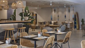 A modern restaurant with wicker furniture, a bar area, and paddleboards on the wall. - Almog Eilat (Eilat)