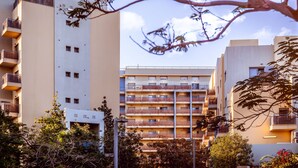 A multi-story building with balconies, a sign, and surrounding vegetation. - Almog Eilat (Eilat)