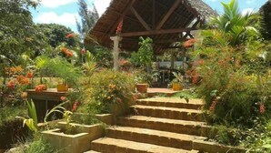 Un jardín con escalones de piedra que conducen a una construcción con techo de paja.