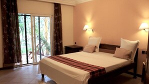 Un dormitorio con cama, dos mesitas de noche, ventana con cortinas y vistas al exterior.