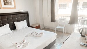 A hotel room with a large bed, a chair, a table, and a balcony with a view. - Maman Hotel (Eilat)