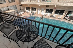 A balcony with a pool, outdoor chairs, and a table. - Maman Hotel (Eilat)
