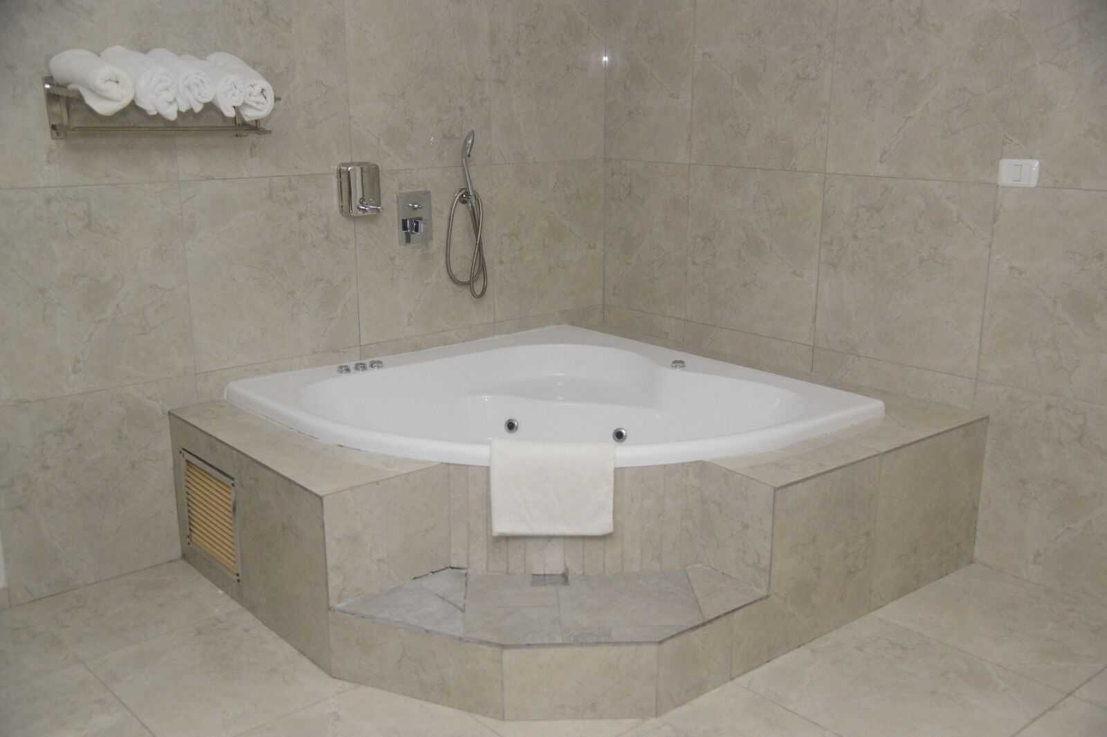 A modern bathroom with a freestanding bathtub, a towel rack with neatly folded towels, and a shower control panel.