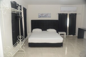 Un dormitorio con una cama, una mesita de noche, aire acondicionado instalado en la pared y un cuadro.