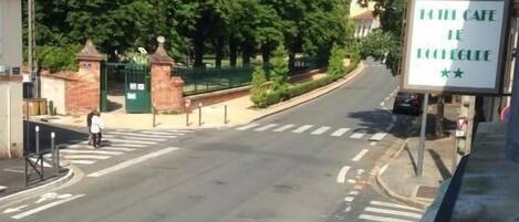A street view with a cafe sign, a pedestrian crossing, and a clear road.