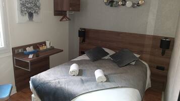 A neatly arranged hotel room with a bed, bedside table, and a small desk with a chair.