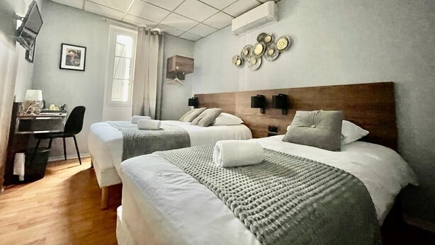 Una habitación de hotel con dos camas, un escritorio y un televisor.