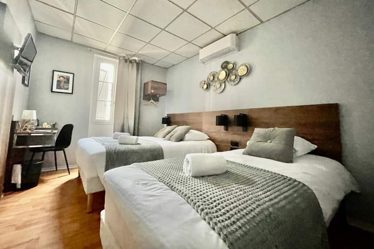 A hotel room with two beds, a desk, and a TV.