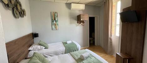 Une chambre d’hôtel avec deux lits, une télévision, une armoire en bois et un tableau au mur.
