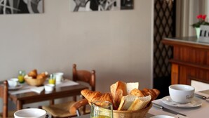 Una mesa con una cesta de cruasanes, un vaso de jugo y una taza blanca.