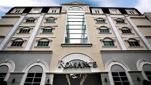 A building with a large arched window and the word "ROMANCE" on the facade. - Romance Hotel Srinakarin (Bangkok)