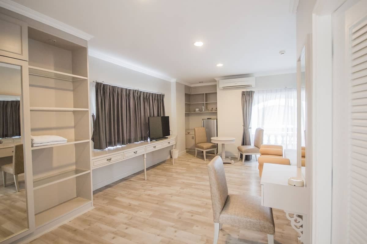 Une pièce moderne et bien éclairée, avec un plancher en bois, une télévision, un bureau, une chaise et une petite table.