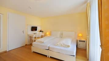 Ein Hotelzimmer mit Doppelbett, Schreibtisch mit Stuhl, Fernseher und Nachttisch mit Lampe.