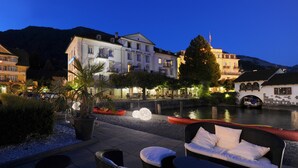 Un hotel junto al río con terraza al aire libre y vistas al agua.