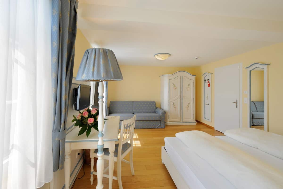 Une chambre à coucher avec un lit, un bureau avec une lampe, un canapé et une armoire.