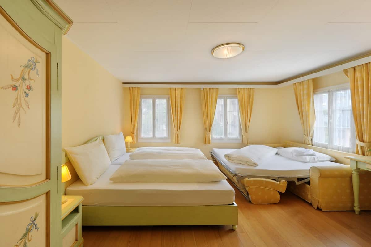 Une chambre d’hôtel avec deux lits, un canapé, un bureau et un luminaire au plafond.