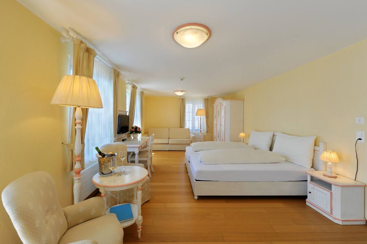 Une chambre d’hôtel comprenant un lit, un canapé, un bureau avec une lampe, une chaise et une armoire.