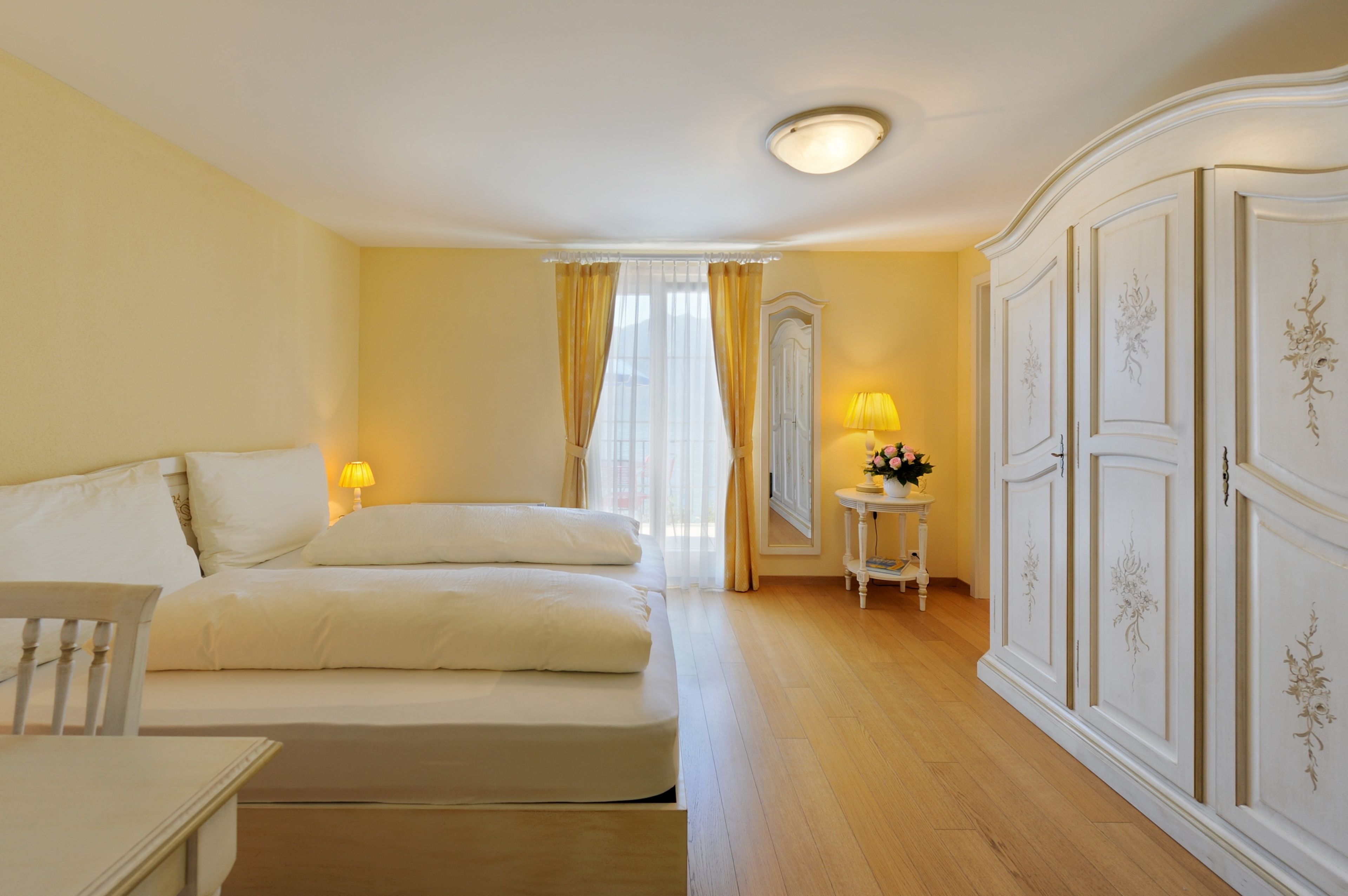 Une chambre d’hôtel avec deux lits, une table de chevet avec une lampe, une armoire et un miroir.