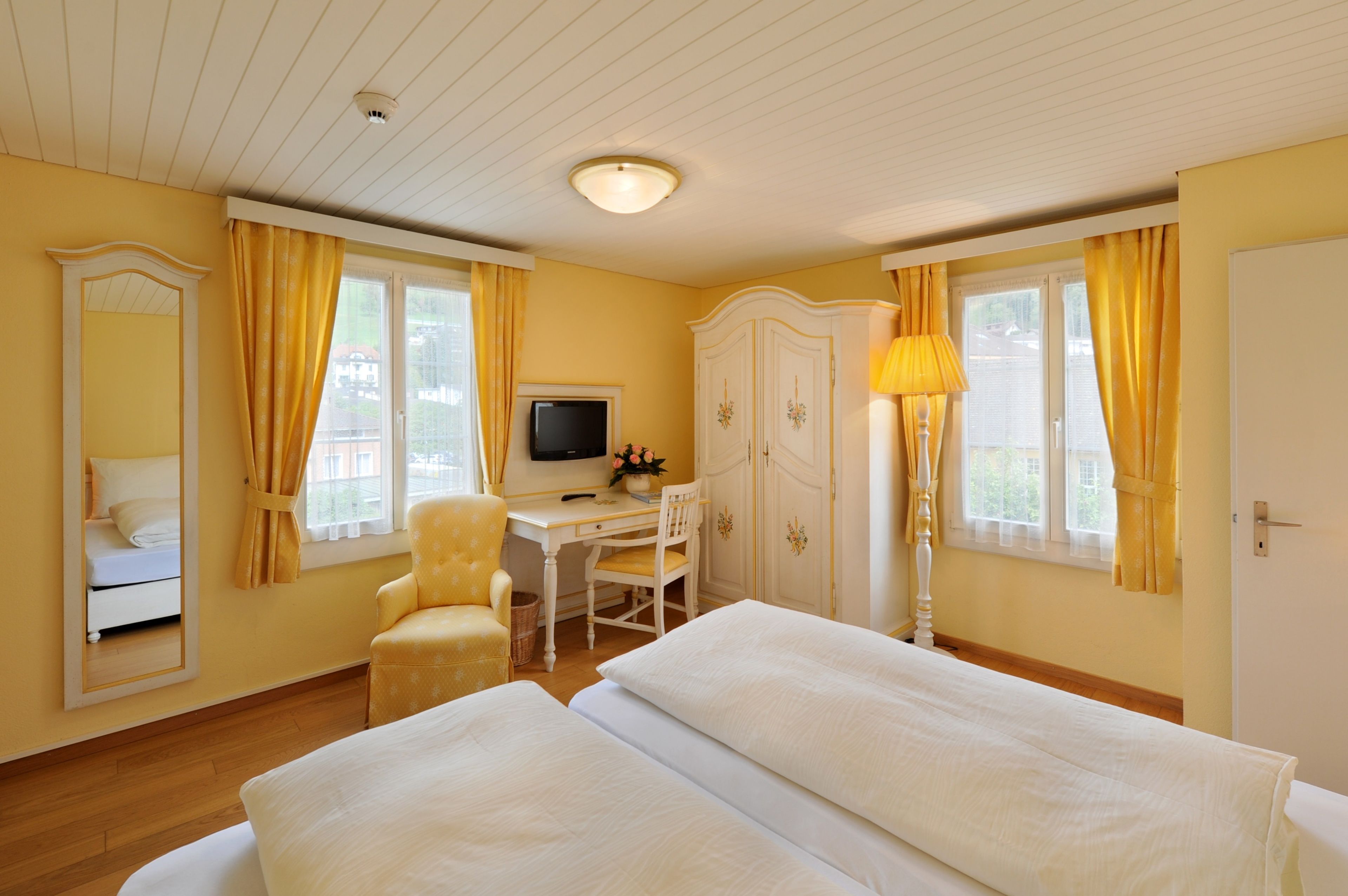 A hotel room with two beds, a desk, a television, and a wardrobe.