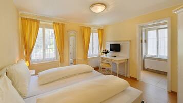 A hotel room with a bed, a desk with a TV, and a window with curtains.