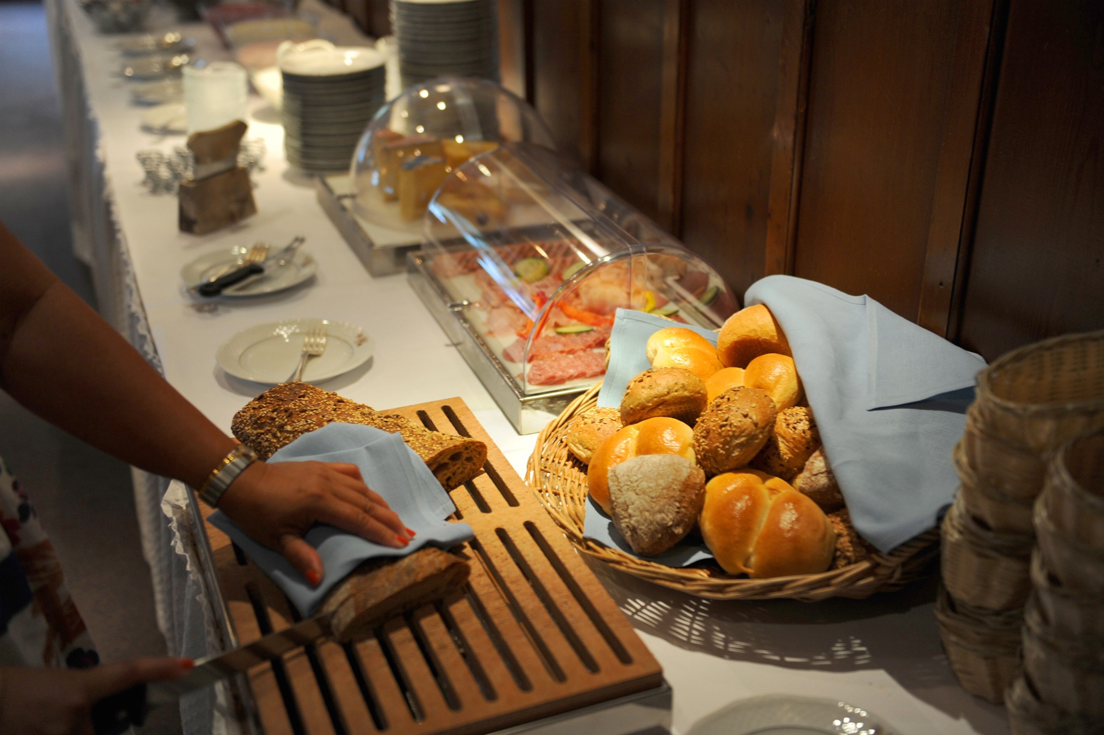 Un buffet proposant une variété de plats et une personne qui distribue du pain.