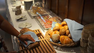 Un buffet proposant une variété de plats et une personne qui distribue du pain.