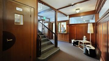 A wooden interior with a staircase, a reception desk, and a telephone sign.